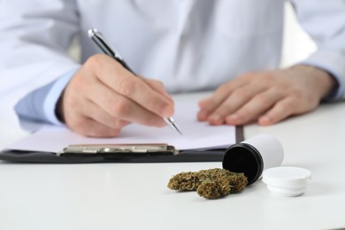 Photo of Doctor writing at table, focus on medical hemp