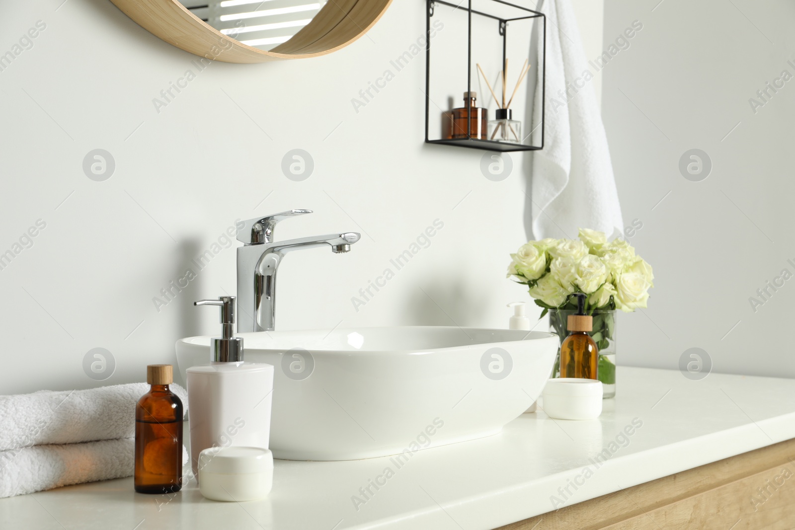 Photo of Bath accessories, sink and roses in bathroom