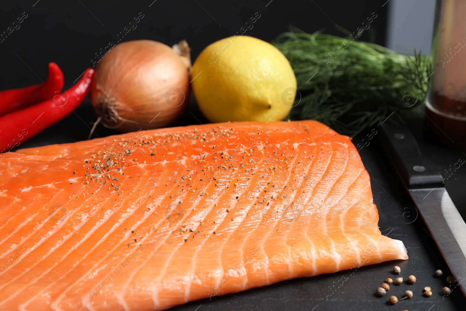 Photo of Fresh raw salmon and ingredients for marinade on black table, closeup