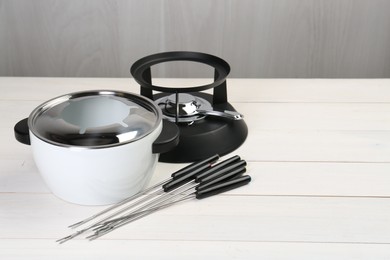 Fondue set on white wooden table, space for text