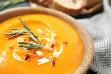 Photo of Delicious pumpkin soup in bowl on table, closeup