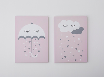 Photo of Adorable pictures of umbrella, cloud and hearts on white wall. Children's room interior elements