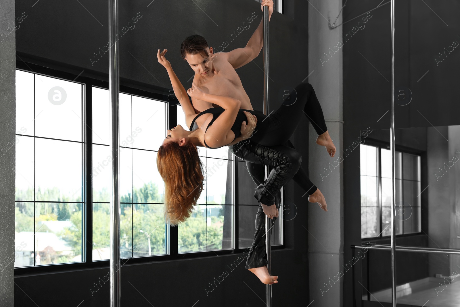 Photo of Young couple dancing in studio with poles