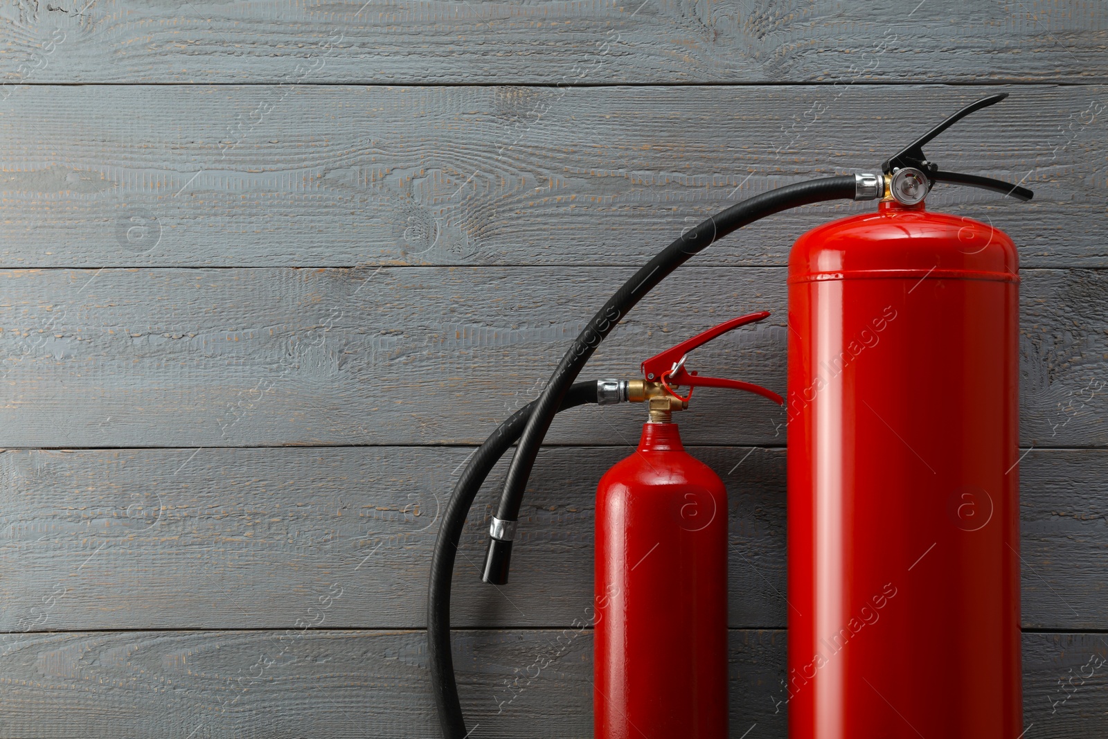 Photo of Fire extinguishers on grey wooden background, flat lay. Space for text