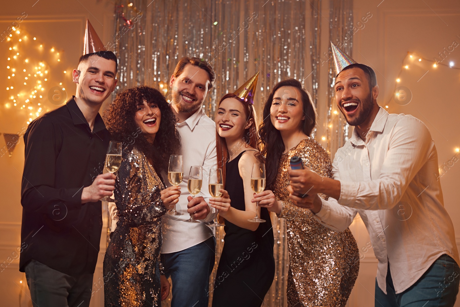 Photo of Happy friends with glasses of sparkling wine celebrating birthday indoors