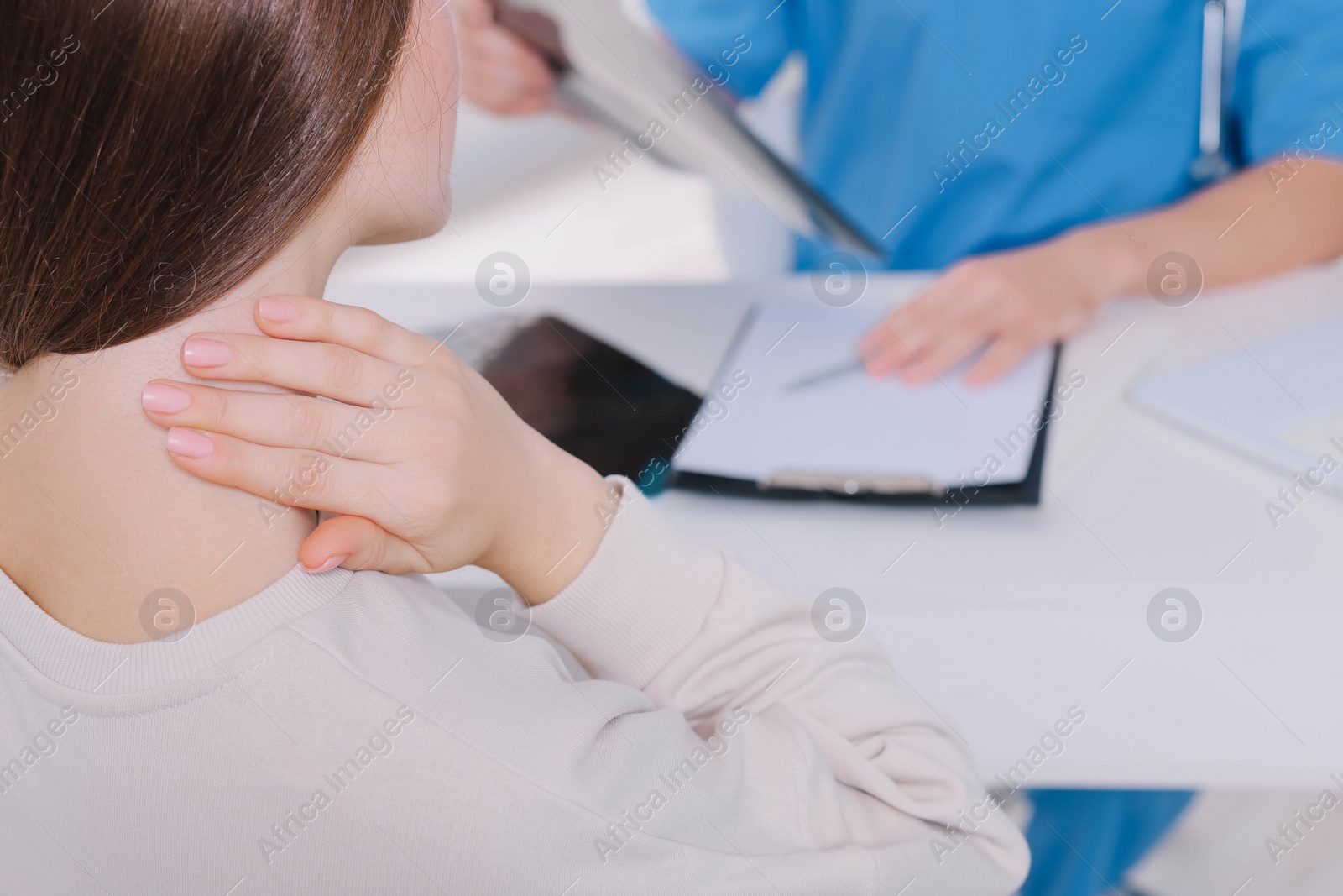 Photo of Doctor with neck MRI image consulting patient in clinic, closeup. Space for text