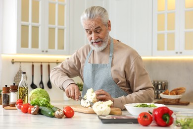 Happy man cutting cauliflower at table in kitchen