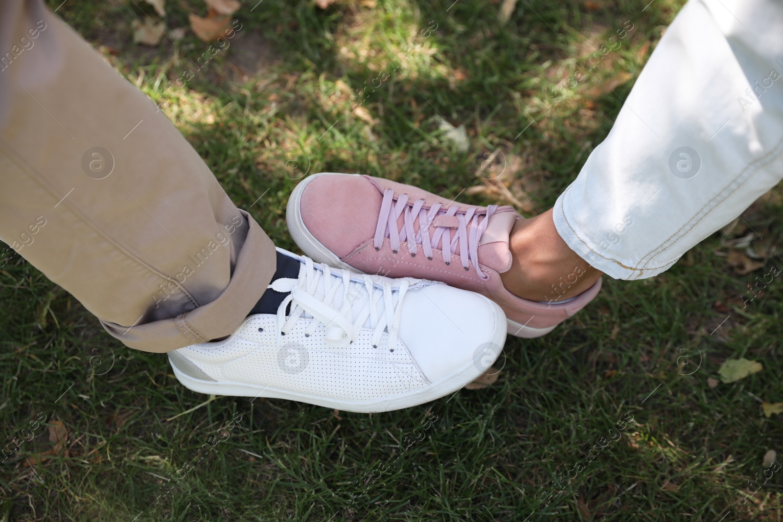 Photo of Man and woman bumping legs to say hello outdoors, closeup. Keeping social distance during coronavirus pandemic