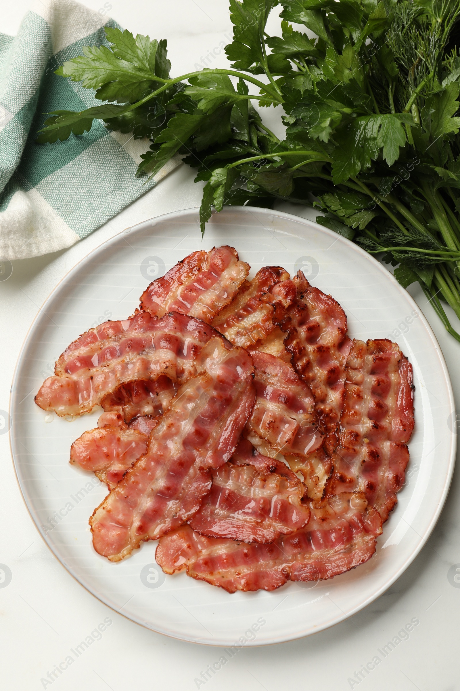Photo of Plate with fried bacon slices and parsley on white table, top view