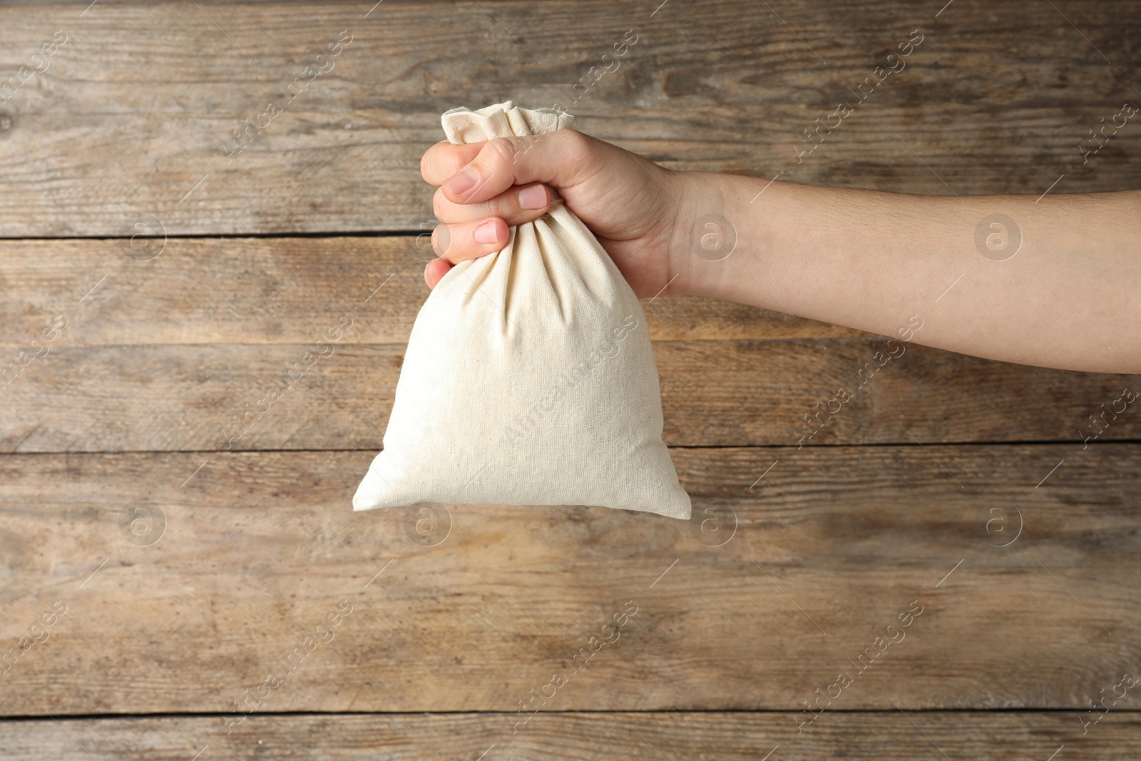 Photo of Woman holding full cotton eco bag on wooden background, closeup