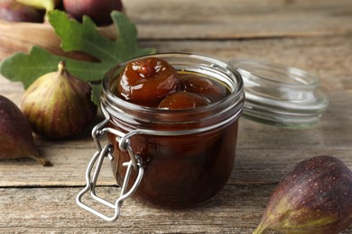 Photo of Jar of tasty sweet jam and fresh figs on wooden table