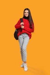 Photo of Happy teenage girl with backpack on yellow background