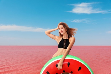 Photo of Beautiful woman with inflatable ring posing near pink lake on sunny day