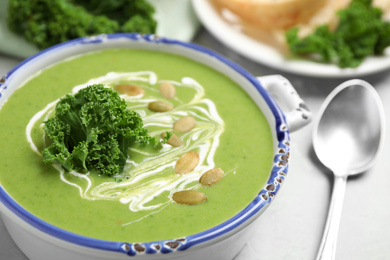 Photo of Tasty kale soup with pumpkin seeds on light grey table, closeup