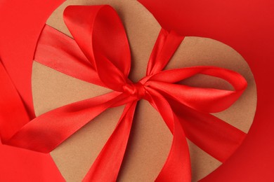 Photo of Beautiful heart shaped gift box with bow on red background, closeup