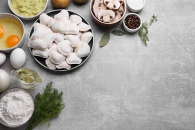 Photo of Raw dumplings (varenyky) and ingredients on grey table, flat lay. Space for text