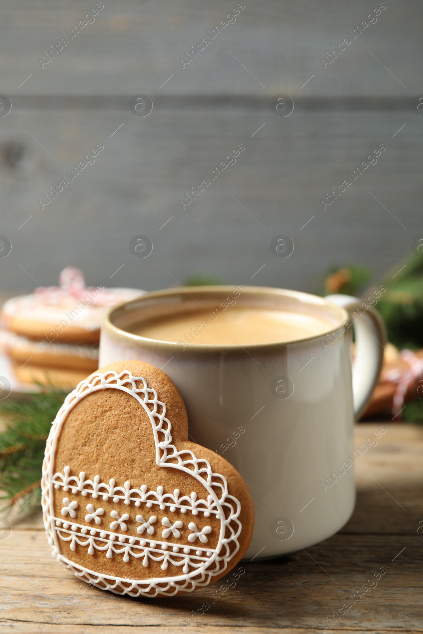 Photo of Tasty heart shaped gingerbread cookie and hot drink on wooden table, closeup