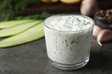Photo of Cucumber sauce in glass bowl with ingredients on table, space for text. Traditional tzatziki