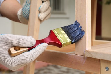 Photo of Man varnishing wooden step stool outdoors, closeup