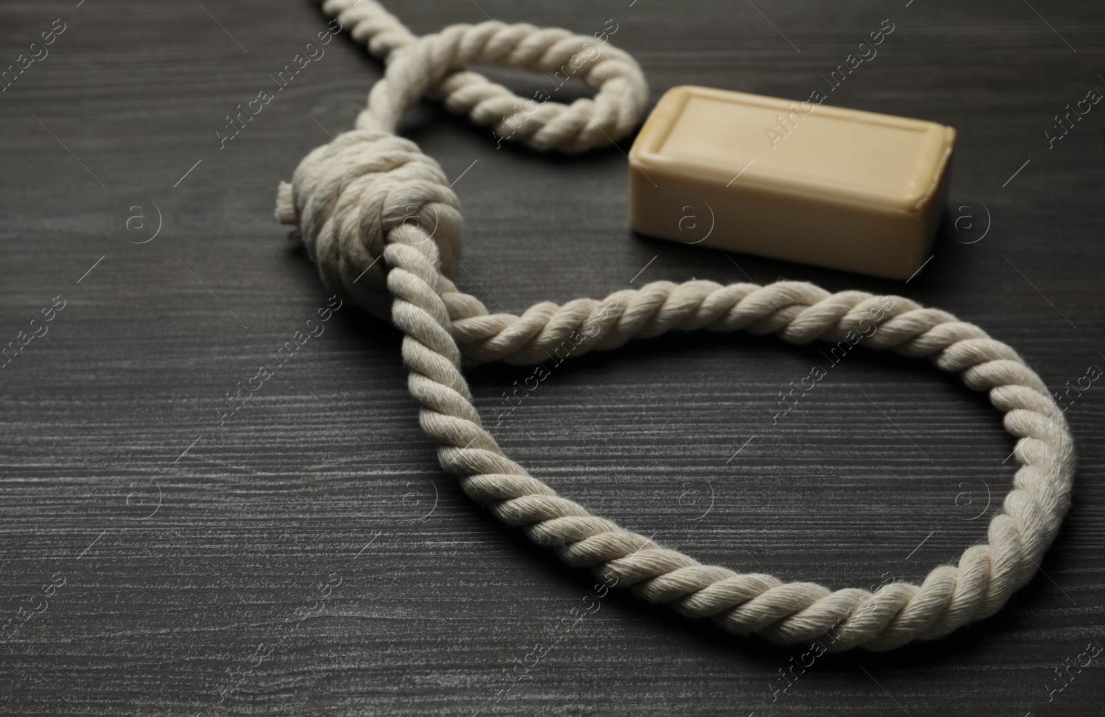 Photo of Rope noose and soap bar on dark wooden table
