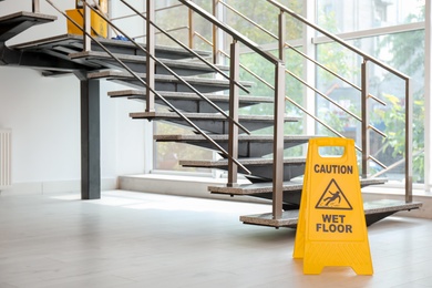 Photo of Safety sign with phrase Caution wet floor near stairs. Cleaning service