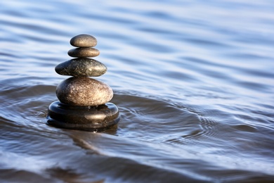 Photo of Stack of dark stones in sea water, space for text. Zen concept