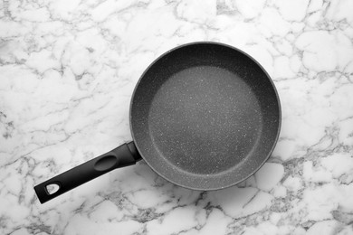 Photo of New non-stick frying pan on white marble table, top view