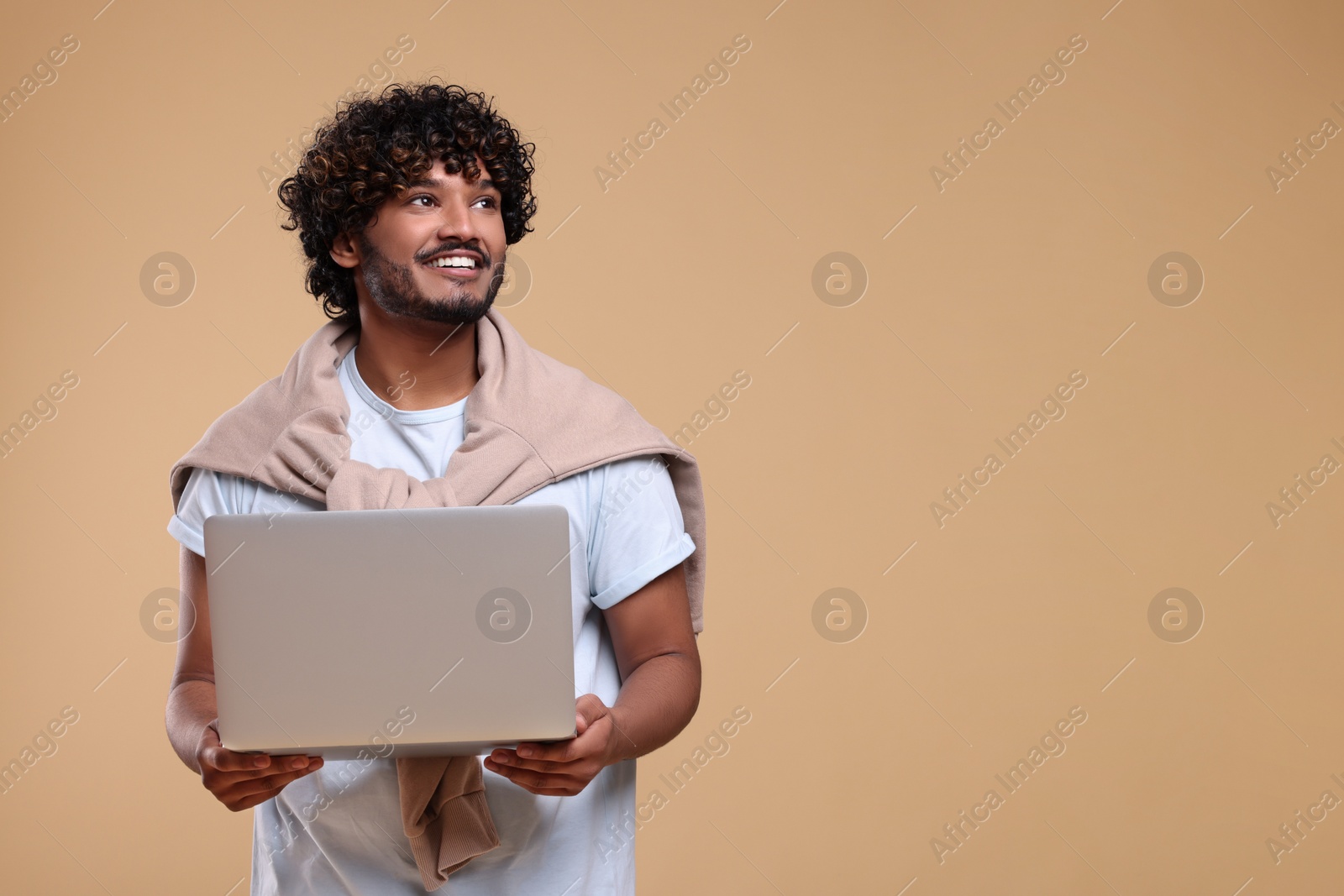 Photo of Smiling man with laptop on beige background, space for text