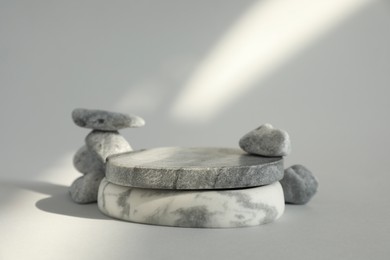 Photo of Presentation for product. Stone podium and pebbles on light grey background. Space for text