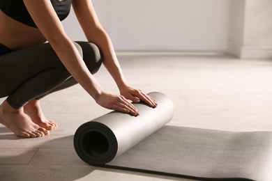 Photo of Woman rolling yoga mat in studio, closeup