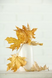 Photo of Beautiful autumn leaves in vase on table against white background, space for text