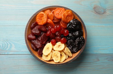 Photo of Mix of delicious dried fruits on light blue wooden table, top view