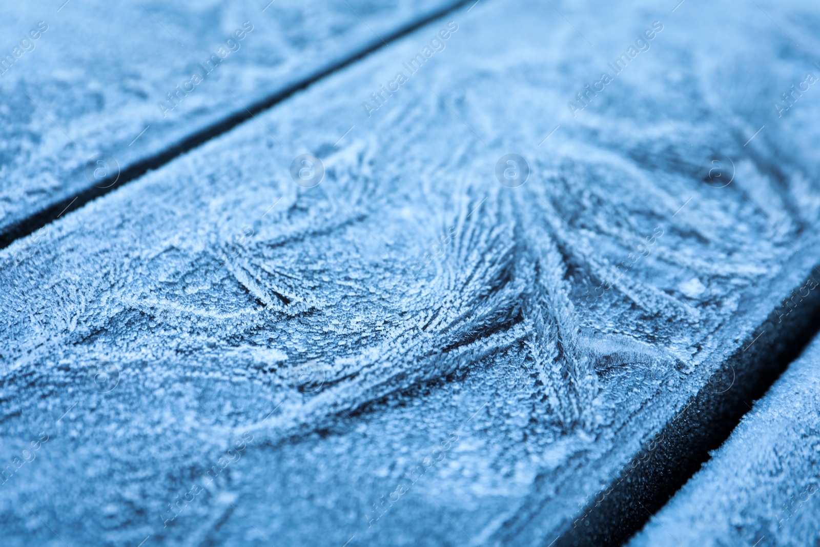 Photo of Beautiful hoarfrost on wooden surface, closeup view