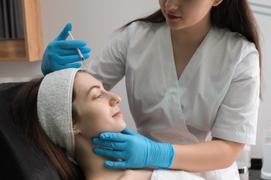 Photo of Cosmetologist giving facial injection to patient in clinic, closeup. Cosmetic surgery