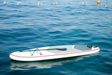 Photo of One SUP board with paddle on water in sea