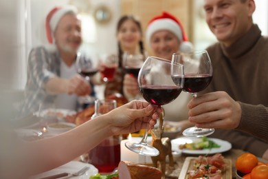 Photo of Family clinking glasses of wine at festive dinner, focus on hands. Christmas celebration