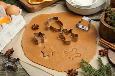Photo of Cookie cutters, dough and ingredients on wooden table. Christmas biscuits