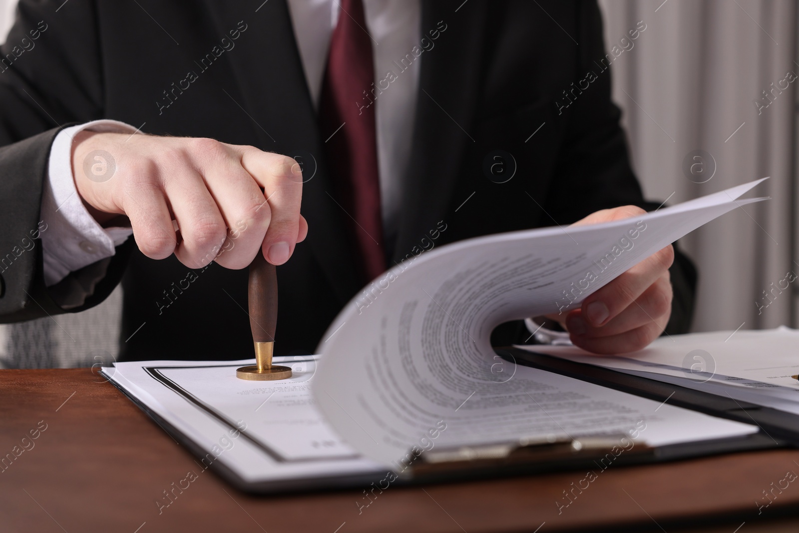Photo of Notary stamping document at table in office, closeup