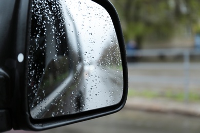 Photo of Closeup of car side rear view mirror with rain drops