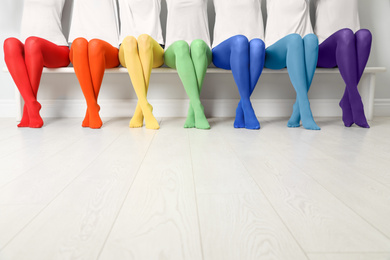 Photo of Women in different colorful tights sitting on bench, closeup