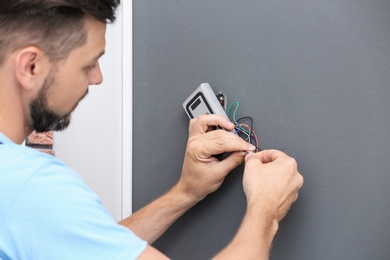 Male technician installing alarm system indoors