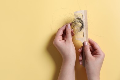 Photo of Woman taking her lost hair from comb on yellow background, top view. Space for text
