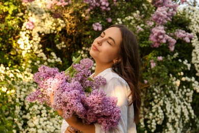 Photo of Attractive young woman with lilac flowers outdoors