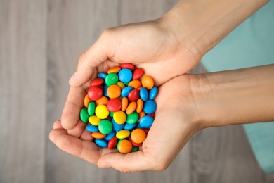 Photo of Woman holding glazed candies on blurred background, top view
