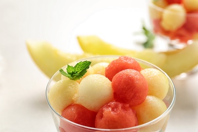 Bowl of melon and watermelon balls and mint on light table, closeup