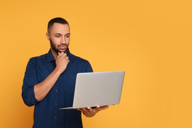 Photo of Thoughtful young man with laptop on yellow background, space for text