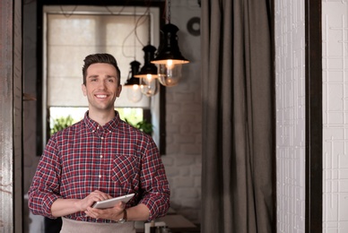 Photo of Young waiter with tablet computer at workplace