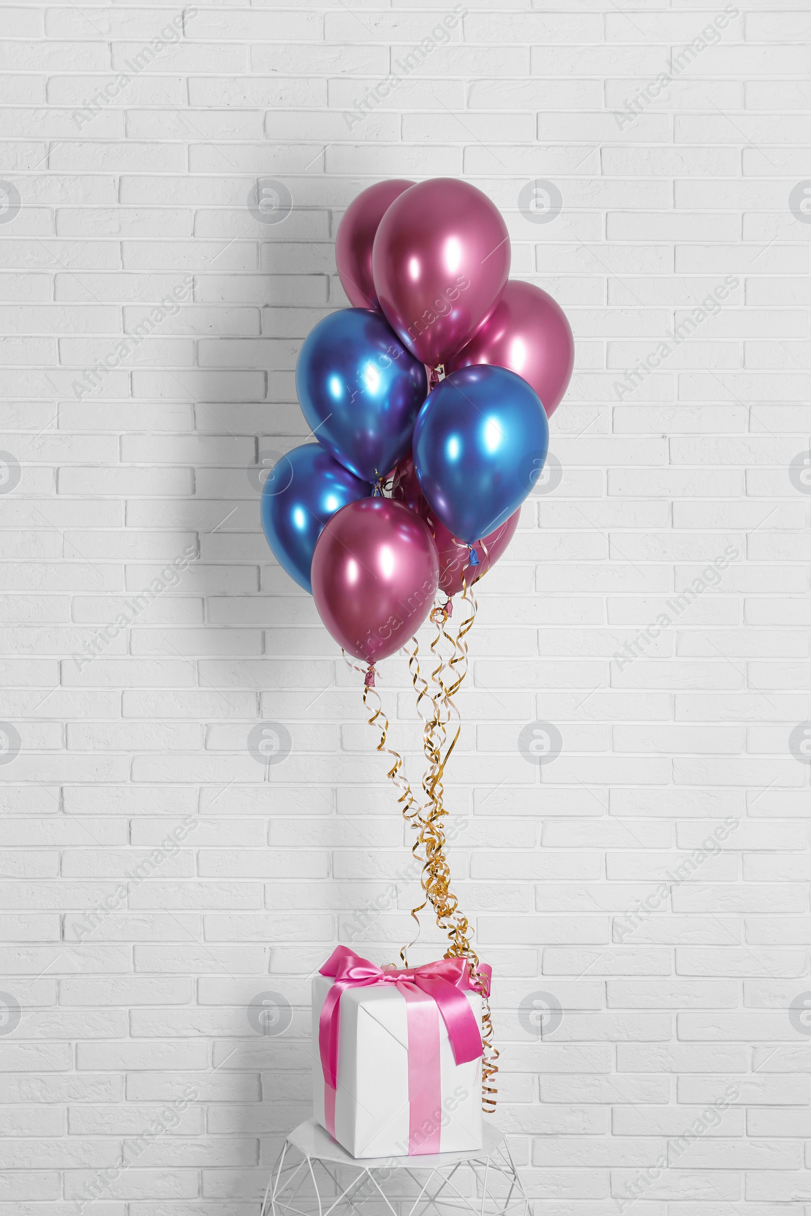 Bright colorful balloons and gift near brick wall. Party time Photo of Bright colorful balloons and gift near brick wall. Party time