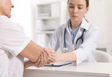 Photo of Arthritis symptoms. Doctor examining patient's elbow in hospital