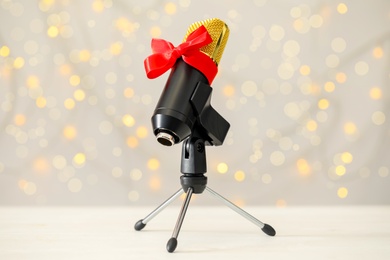 Photo of Microphone with red bow on table against blurred lights. Christmas music